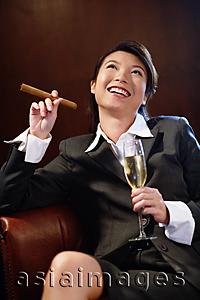 Asia Images Group - Businesswoman holding glass of champagne and cigar, looking up