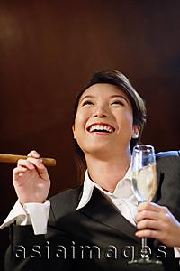 Asia Images Group - Businesswoman with glass of champagne and cigar, looking up,