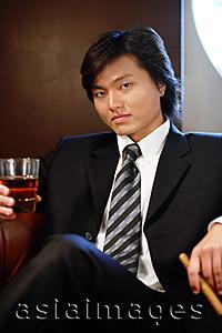 Asia Images Group - Businessman holding glass and cigar, looking at camera, portrait