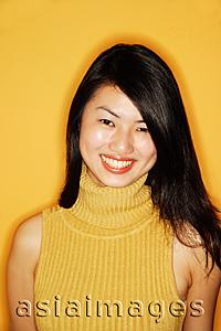 Asia Images Group - Young woman in yellow turtleneck, smiling at camera, portrait