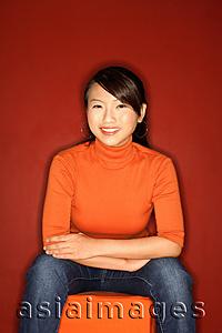 Asia Images Group - Young woman sitting, arms crossed, smiling at camera