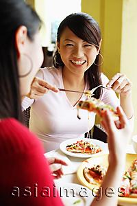 Asia Images Group - Young women eating pizza at cafe, over the shoulder view
