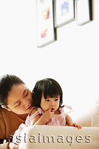 Asia Images Group - Mother with baby girl, on sofa, looking away