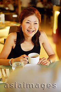 Asia Images Group - Couple in cafe, woman holding cup, over the shoulder view