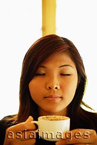 Asia Images Group - Young woman holding cup of coffee, eyes closed