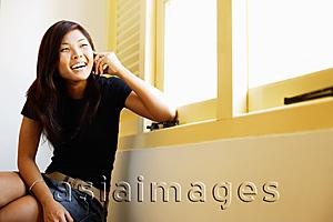 Asia Images Group - Young woman sitting, using mobile phone
