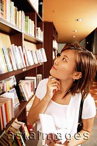 Asia Images Group - Young woman holding book, hand on chin, looking up