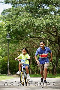 Asia Images Group - Girl cycling away, father running behind her