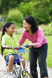 Asia Images Group - Young girl on bicycle, mother next to her