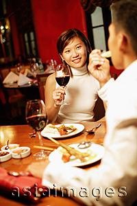Asia Images Group - Couple at restaurant, woman holding wine glass, man eating