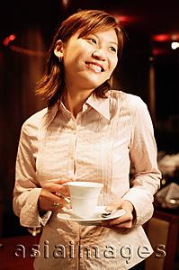 Asia Images Group - Woman holding cup and saucer, smiling