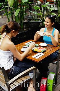Asia Images Group - Two women at cafe, having coffee and food