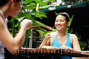Asia Images Group - Two women at outdoor cafe, drinking coffee