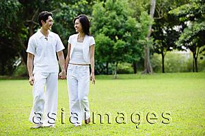 Asia Images Group - Couple holding hands, walking across field