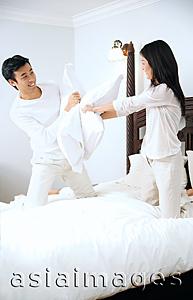 Asia Images Group - Couple on bed, having a pillow fight
