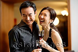 Asia Images Group - Couple holding wine glasses, laughing