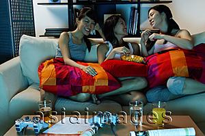 Asia Images Group - Three young women in living room, sitting on sofa