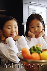 Asia Images Group - Two girls looking at a bowl of vegetables