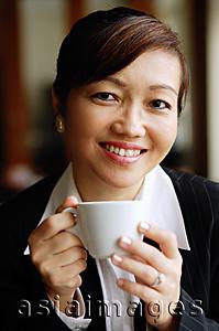 Asia Images Group - Businesswoman holding cup, looking at camera