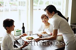 Asia Images Group - Two women in restaurant, waitress serving their food