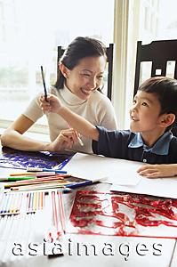 Asia Images Group - Mother sitting with son, colour pencils and drawing paper on the table, son holding pencil, looking up