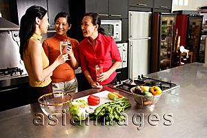 Asia Images Group - Three women in kitchen, holding wine glasses, talking