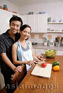 Asia Images Group - Couple standing in kitchen, woman chopping vegetables, smiling at camera