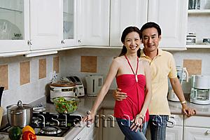 Asia Images Group - Couple standing in kitchen, smiling at camera, portrait