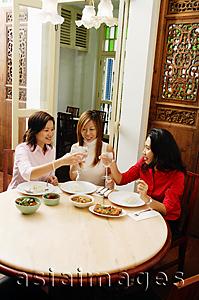 Asia Images Group - Women sitting at restaurant table, toasting