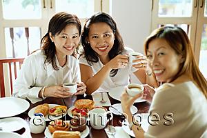 Asia Images Group - Three women having tea at cafe, smiling at camera