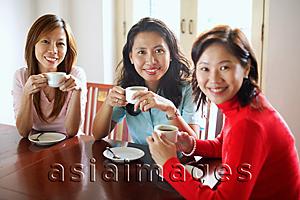 Asia Images Group - Women in cafe holding cups, smiling at camera