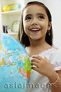 Asia Images Group - Young girl standing in front of globe, looking away