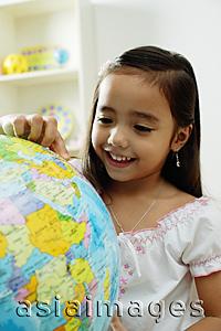Asia Images Group - Young girl pointing at a globe