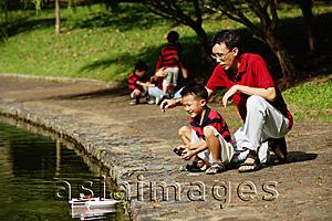 Asia Images Group - Father with son, playing with remote control boat