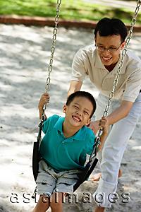 Asia Images Group - Father and son in playground, father pushing son on swing