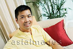 Asia Images Group - Man sitting on sofa, looking at camera
