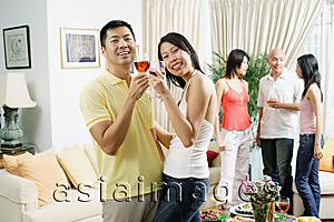 Asia Images Group - Couple in living room, toasting with wine glasses, smiling at camera