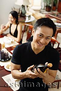 Asia Images Group - Man looking at camera, holding wine bottle