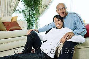 Asia Images Group - Couple in living room, smiling at camera, portrait