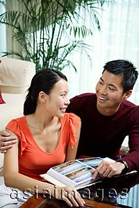 Asia Images Group - Couple at home, photo album in front of them