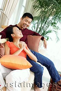 Asia Images Group - Couple in living room, sitting on sofa, woman with hands clasped