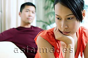 Asia Images Group - Couple at home, woman in front, looking away, hand on chin