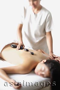 Asia Images Group - Masseuse placing stones on womans back