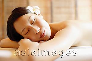 Asia Images Group - Woman on massage table leaning head on arms, eyes closed
