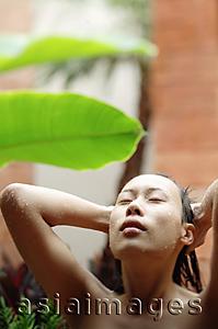 Asia Images Group - Woman with eyes closed, hands on head, taking outdoor shower