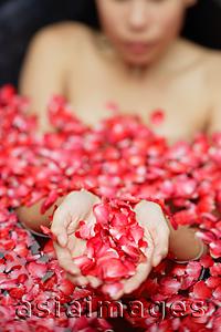Asia Images Group - Woman in tub holding flower petals in cupped hands