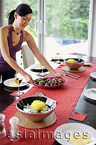 Asia Images Group - Young woman setting the dining table