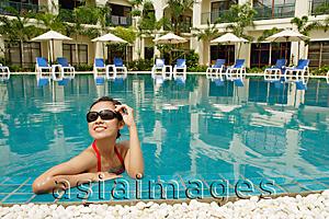 Asia Images Group - Woman in swimming pool, adjusting sunglasses, smiling