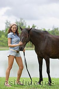 Asia Images Group - Woman standing with horse, smiling at camera