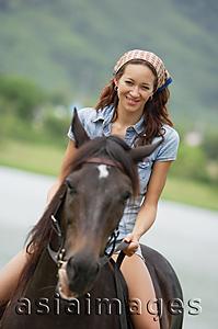 Asia Images Group - Woman sitting on horse, smiling